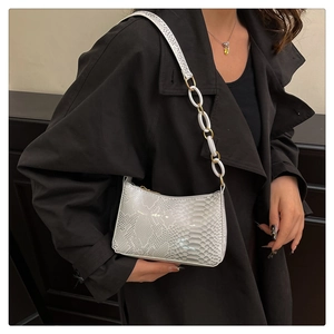 Détail du sac à bandoulière motif serpent avec chaîne blanche et sangle en similicuir