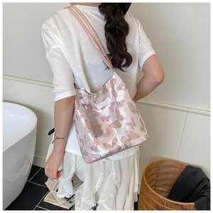 Détail du sac cabas en satin rose avec broderie papillon et gland en soie sur mannequin
