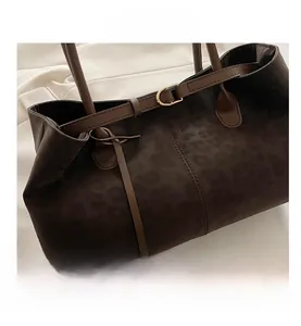 Detail of leopard print suede tote bag with brown leather strap and gold buckle