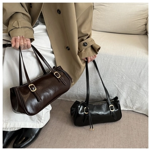 Close-up of retro cylinder handbags with golden metal buckles and glossy leather texture