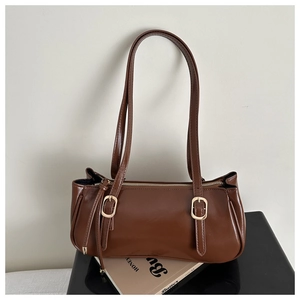 Detail of dark brown leather Boston bag with gold buckle hardware and dual shoulder straps