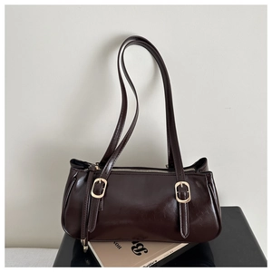 Close-up of dark brown Boston bag with polished texture and gold buckle details