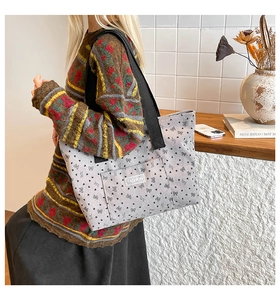 Detail of light gray canvas tote bag with black heart print and fashion label