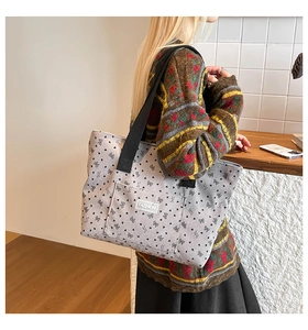 Close-up of corduroy tote bag featuring black bows, heart prints and fashion label