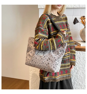 Detail of velvet tote bag with bow prints and FASHION label on model's shoulder
