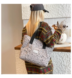 Detail of light grey canvas tote bag featuring black bow patterns and Fashion label tag