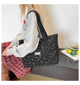 Detail of black corduroy tote with heart print and fashion label on wide shoulder strap