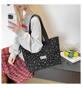 Detail of black tote bag with white bow patterns and fashion label worn by a model