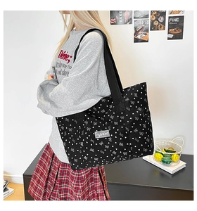 Close-up of black tote bag featuring white heart and bow prints on durable canvas