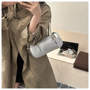 Detailed side view of metallic silver baguette bag with buckles in a lifestyle setting