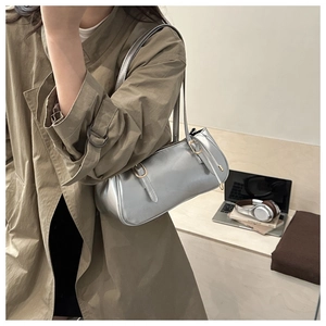 Detail of silver metallic baguette bag with golden buckle and sleek shoulder straps