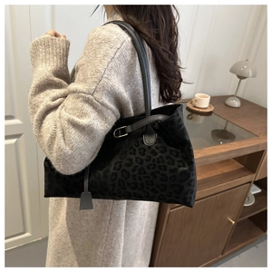 Detail of black tote bag showing smooth texture and leopard print pattern on the side