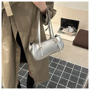 Detail of silver metallic shoulder bag with adjustable gold buckles on twin straps