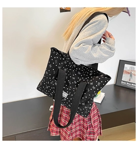 Canvas tote bag with heart and bow patterns worn over the shoulder in a casual setting