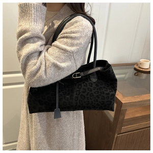 Close-up of leopard print tote bag worn on shoulder over a cozy knit sweater