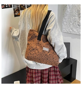 Detail of large brown corduroy tote with heart patterns and black shoulder straps