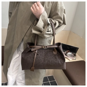 Close-up of leopard print tote bag with brown leather handles and gold buckle detail