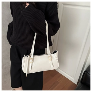 Close-up of white minimalist shoulder bag with gold buckles and adjustable straps