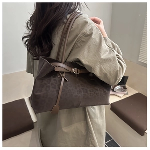 Close-up of brown leopard print tote bag with metallic ring and leather straps detail