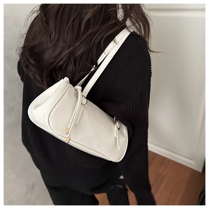 Detail of white baguette shoulder bag on black knitwear with golden metal buckle