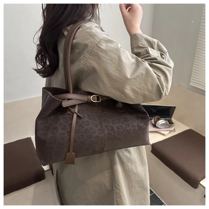 Detail of leopard print tote bag with gold metal buckle shown on a trench coat