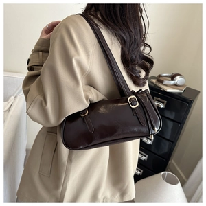 Detail of dark brown glossy leather shoulder bag with adjustable gold buckle and drawstring