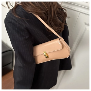 Modern glossy beige baguette bag with gold twist lock shown on model with blazer