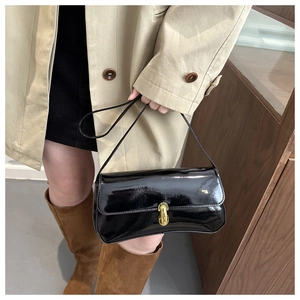 Close-up of a chic black patent leather shoulder bag with a stylish gold clasp lock detail