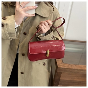 Close-up of a red glossy patent leather baguette bag featuring a gold metal buckle