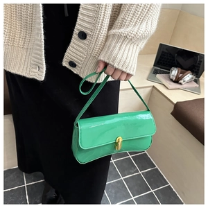 Detail of green patent leather underarm bag with gold cylindrical metal twist lock