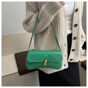 Detail of emerald green patent leather shoulder bag with golden twist-lock buckle