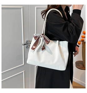 Detail of white leather tote bag with elegant brown floral silk scarf on handle
