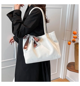 Detail of white suede tote bag featuring a decorative brown floral scarf on the long handle