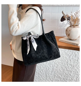 Detail of minimalist black matte tote bag with silk scarf on a white sweater model