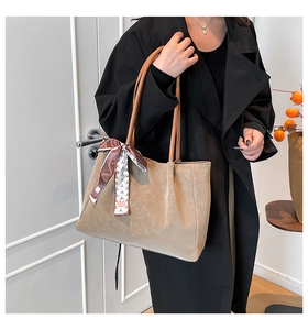 Détail du cabas taupe à texture mate avec poignées marron et foulard décoratif en soie