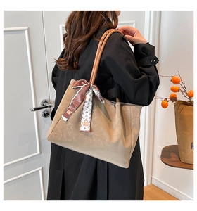 Detail of a large khaki pleated tote bag with a floral scarf on the shoulder of a model