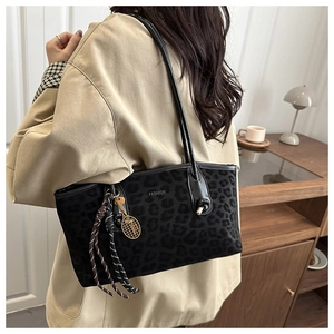 Détail du sac cabas léopard avec anses en cuir noir et breloque raquette de tennis dorée