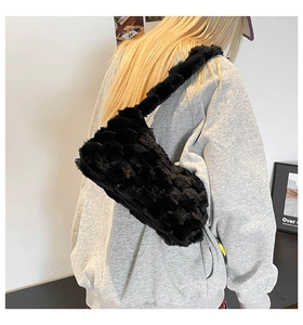 Detail of black faux fur shoulder bag with textured woven pattern and plush strap