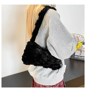 Detailed back view of a black fluffy faux fur shoulder bag worn by a model in a modern room