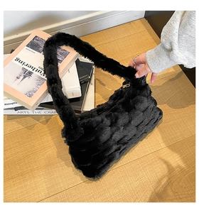 Detail of black plush crossbody bag with quilted bubble texture on a wooden table