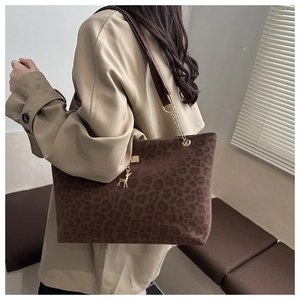 Detail of leopard print tote bag with gold chain strap and deer charm on beige coat