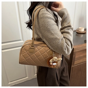 Detail of khaki quilted bowling bag featuring a plush doll charm on a stylish model