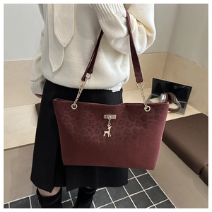 Dettaglio borsa tote bordeaux maculata con catena dorata e ciondolo a forma di cervo