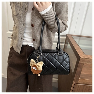 Detail of black quilted shoulder bag with plush butterfly charm and gold hardware