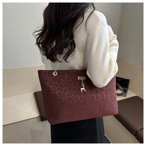 Détail du sac cabas bordeaux avec motif léopard et breloque cerf doré sur le modèle