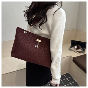Close-up of leopard print burgundy tote bag with gold deer charm and chain detail