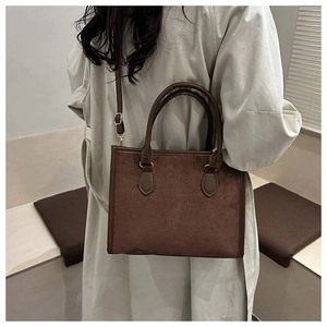 Close-up of dark brown tote bag featuring clover embossing and detachable shoulder strap