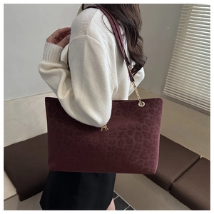 Détail du sac cabas bordeaux à motif léopard avec pendentif cerf doré et chaîne