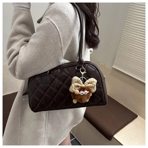 Detail of dark brown quilted bowling bag with a cute fuzzy monster keychain accessory