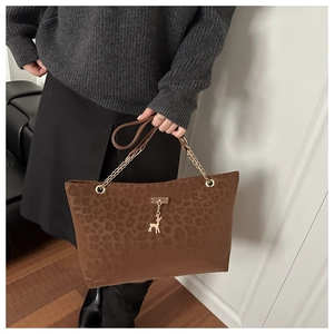 Detail of leopard print tote bag with gold chain strap and deer charm accessory